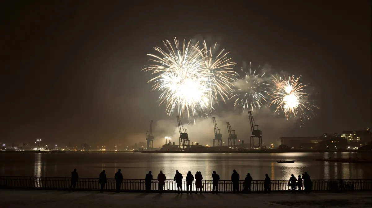 Silvesterfeuerwerk über der Elbe, von den Landungsbrücken aus mit Hafenkränen im Hintergrund